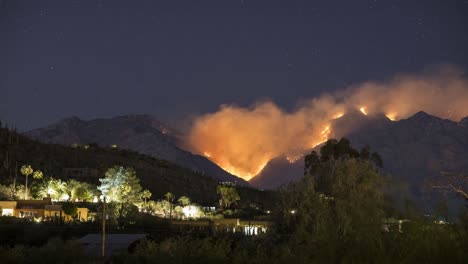 timelapse of wildfire and smoke at night above houses in residential area