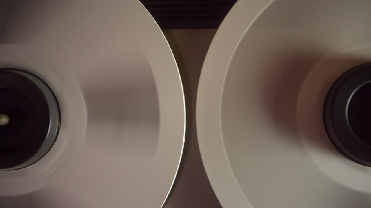 fotografía de cerca de los carretes girando en retroceso en un grabador de cinta vintage en el estudio de grabación