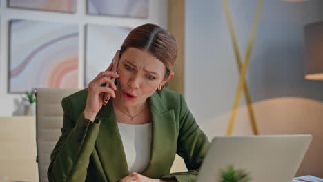 frustrated employee speaking mobile phone at desk closeup. woman feeling nervous