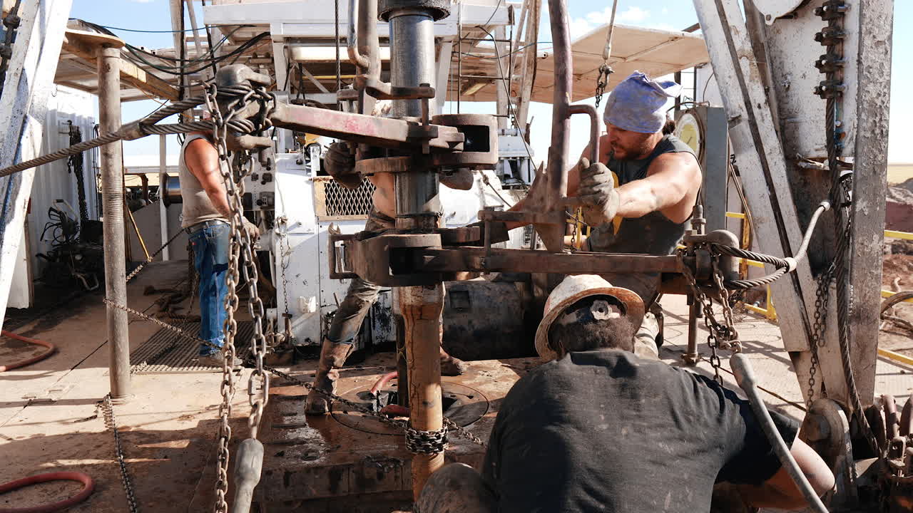 Hard-working men at the site for oil production. Workers arrange the equipment for drilling resources.