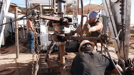 hard-working men at the site for oil production. workers arrange the equipment for drilling resources.
