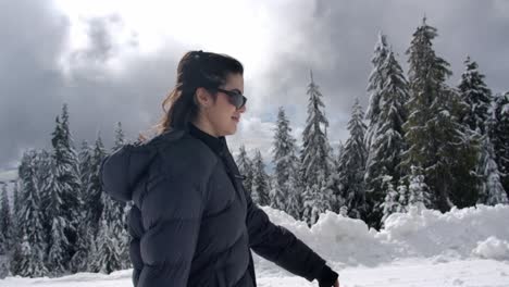 retrato de una mujer con ropa de invierno y gafas de sol caminando por la naturaleza de invierno
