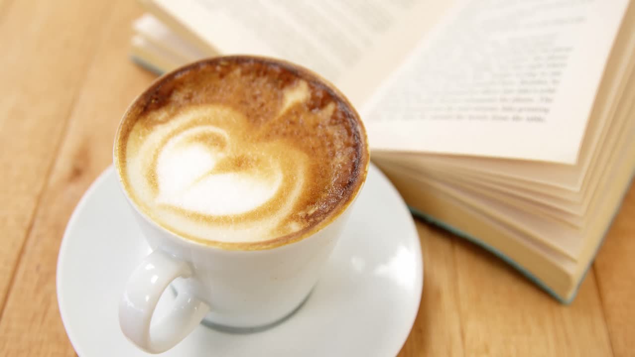 Close-up of coffee cup with open book