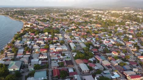 Aerial-footage-of-a-coastal-town-during-sunset,-highlighting-residential-homes,-streets,-and-the-serene-coastline