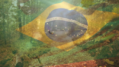 digital composition of brazil waving flag over autumn leaves falling against forest pathway