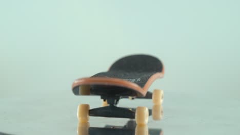 a beautiful detailed close-up shot of a mini skateboard, tiny white wheels, fingerboard on a 360 rotating stand, shiny mirror reflection, professional lighting, cinematic 4k video tilt up