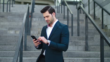 Closeup-businessman-laughing-at-street.-Man-using-modern-smartphone-outside