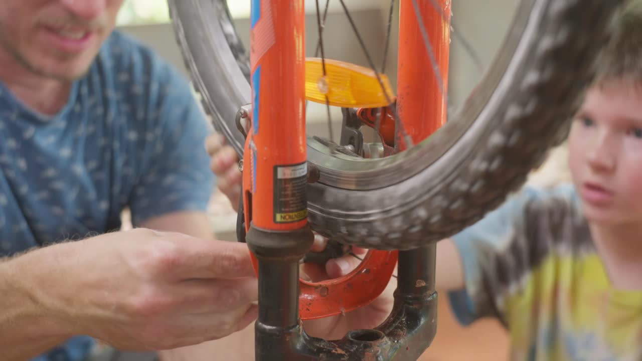 Man and his son working together, Dad is teaching his son about tools and fixing his bicycle. Clip 5