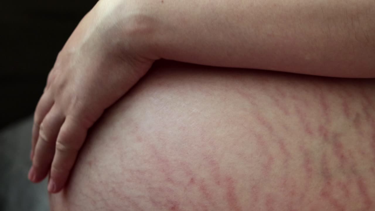 Close up of pregnant woman lovingly rubbing her belly. Dark background