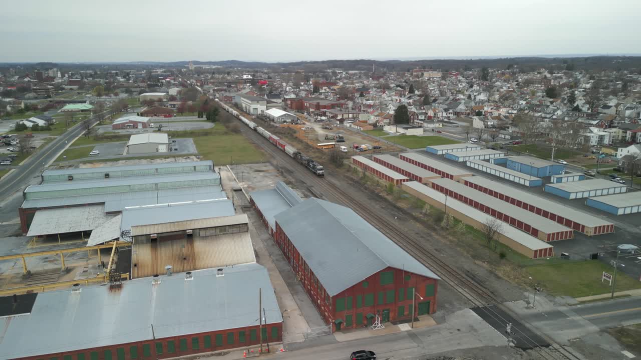 Luftaufnahme mit Drohne eines Zuges, der durch eine riesige Industrieanlage fährt.