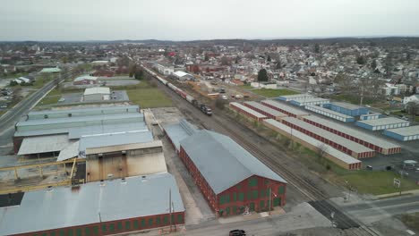 Aerial-drone-view-of-train-commuting-through-massive-industrial-facility