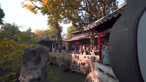 tourists standing, sitting, looking and enjoying the pond and yuyuan garden