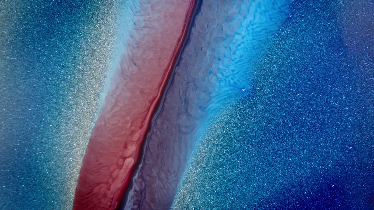 화려한 파란색과 분홍색 잉크가 물 속에 분산되어 반이는 입자들로 조용하고 우주적인 분위기를 불러일으킨다.