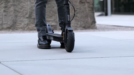 primer plano de un hombre de negocios caminando hacia su scooter eléctrico y alejándose