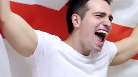 english young man celebrating while holding the flag of england in slow motion