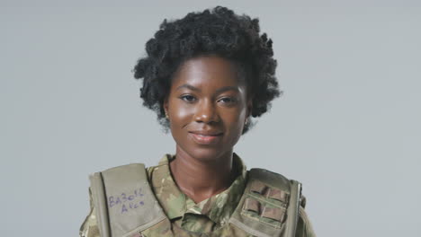 Studio-Portrait-Of-Smiling-Young-Female-Soldier-In-Military-Uniform-Against-Plain-Background