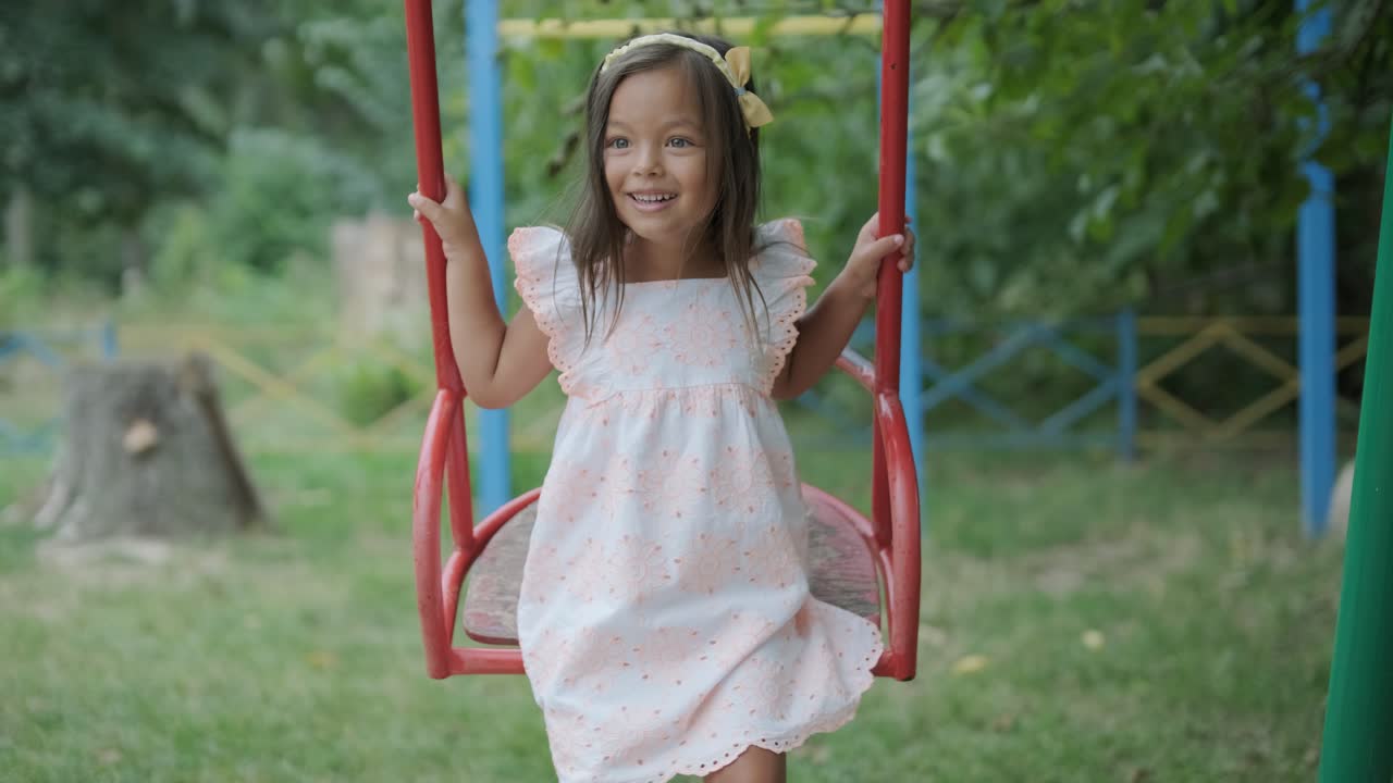 una madre embarazada y su hija joven disfrutan de un tiempo de juego juntos en un patio de recreo en el parque, rodeados de árboles y vegetación