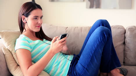 Pretty-brunette-relaxing-on-the-sofa-listening-to-music