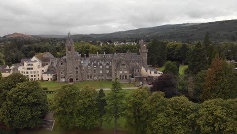 Dramatic-aerial-reveal-of-Fort-Augustus-Abbey-on-shore-of-Loch-Ness,-Scotland