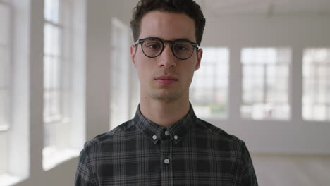 retrato en primer plano de un atractivo joven hipster que mira en serio a la cámara en un nuevo apartamento con gafas