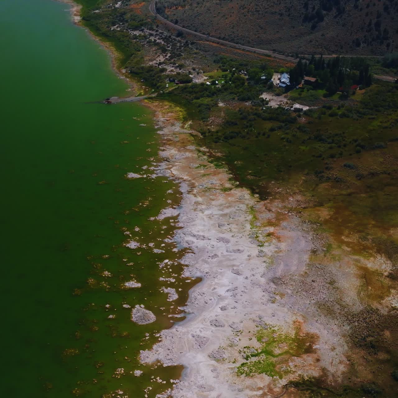 Beautiful scenery of Mono Lake, California, United States. White salty scurf on the waterfront verging with green grass and then mountain