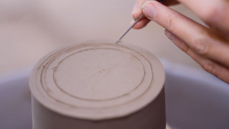 potter scores clay on pottery wheel from two different angles