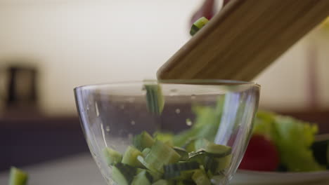 cucumber pieces fall down into glass bowl on table macro