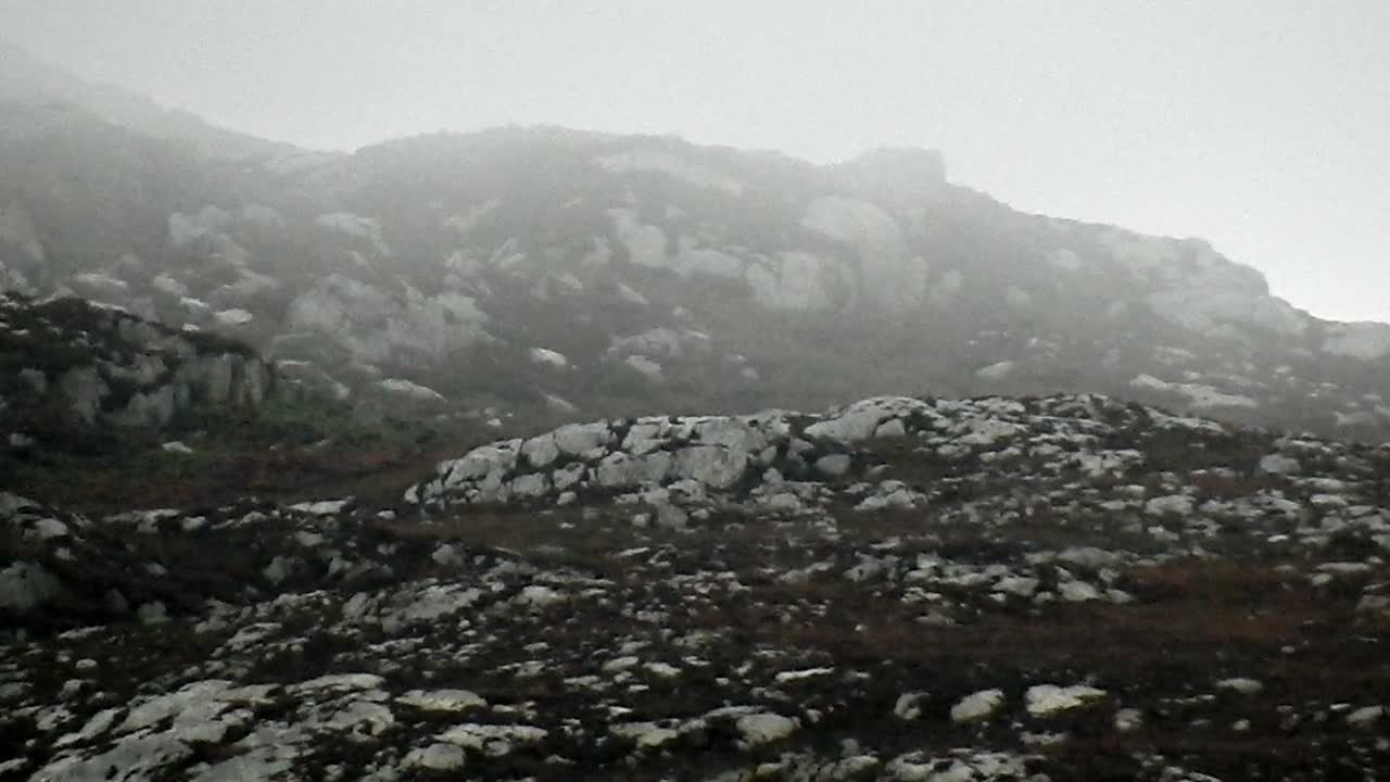 Rainy mist floating across rugged rocky mountain slopes on top of Holyhead mountain North Wales