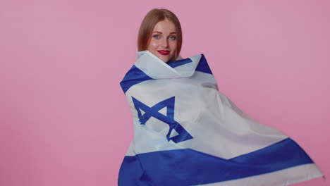 Alegre-Y-Encantadora-Adolescente-Ondeando-Y-Envolviendo-La-Bandera-Nacional-De-Israel,-Celebrando-El-Día-De-La-Independencia