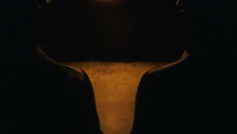 two men in full body latex suits walk towards a black background