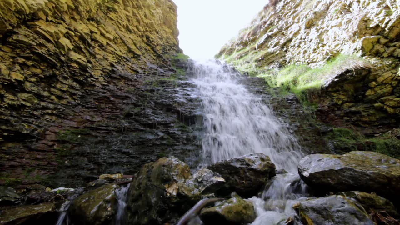 water flowing over a waterfall crashing down down onto polished rocks