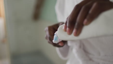 Hands-of-african-american-attractive-woman-applying-toothpaste-on-the-brush-in-bathroom