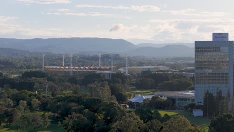 drone footage captures gold coast's skyline with a focus on carrara stadium and surrounding greenery under soft daylight