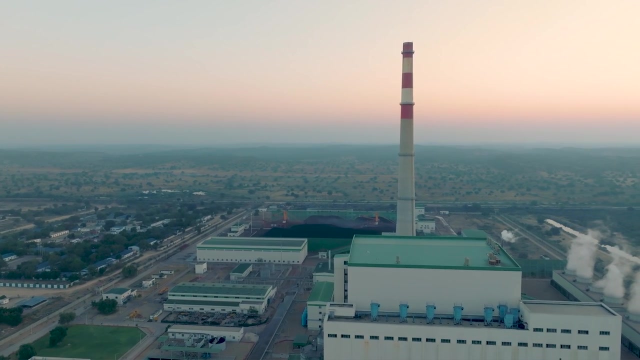 Drone ascends toward a smokestack then pans over Pakistan's power plant at dusk.