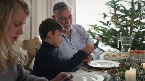 cute boy showing his grandfather how to use mobile phone.