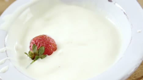 fresa cayendo en la crema batida