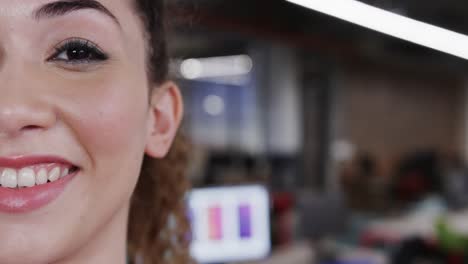 Half-portrait-of-happy-biracial-female-creative-at-casual-office,-with-copy-space,-in-slow-motion