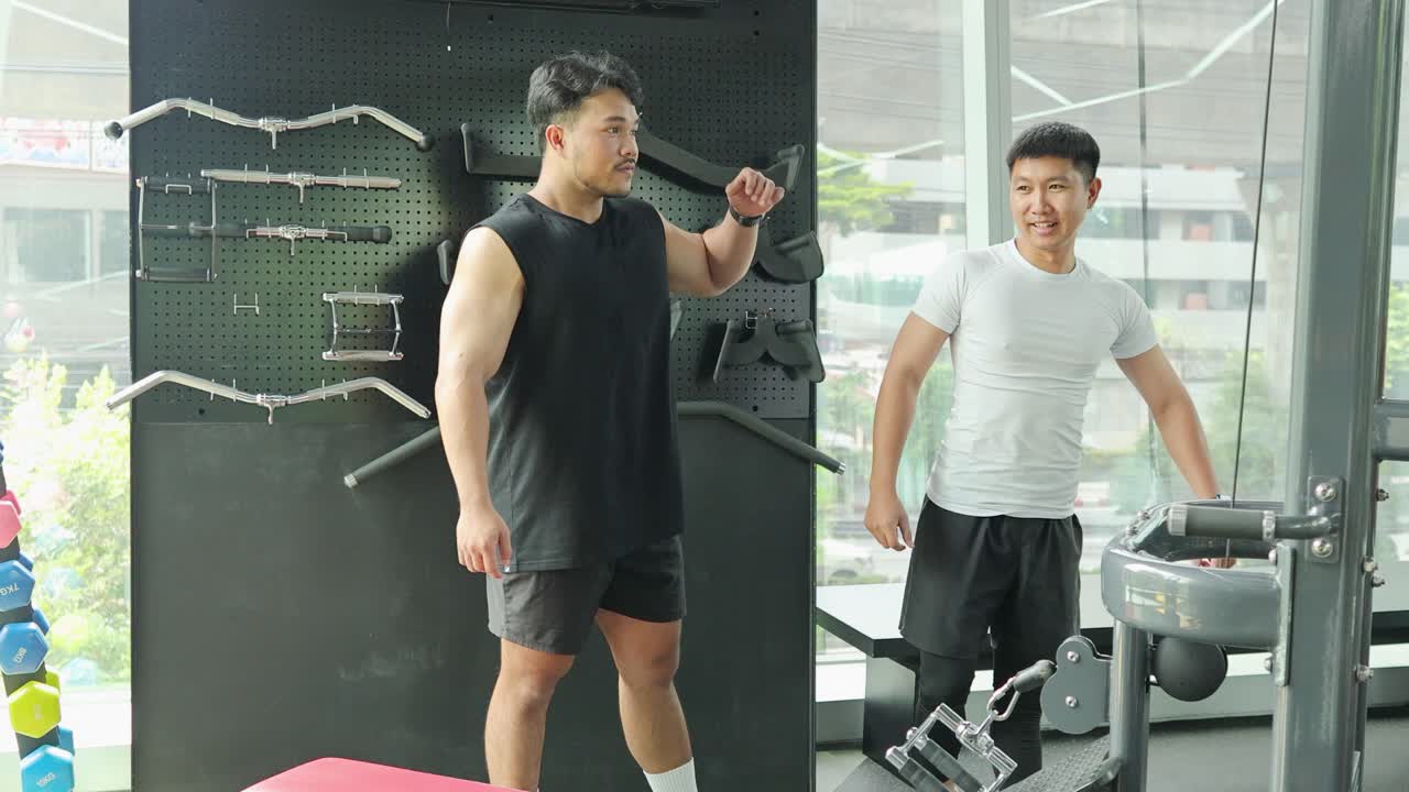 Two men engage in a gym workout session, focusing on strength training with a personal trainer guiding the exercises