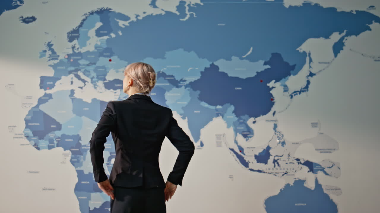 Thoughtful employee analyzing world map back view. Businesswoman brainstorming