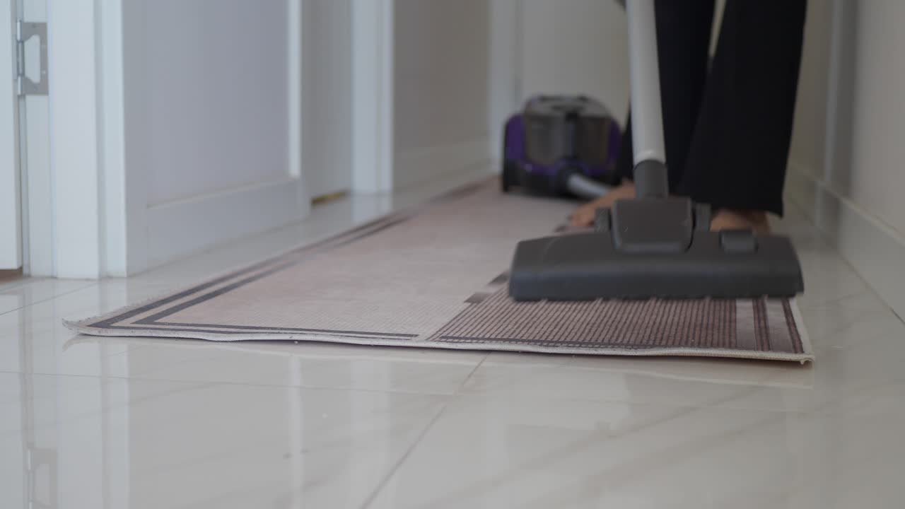 Person Vacuuming a Hallway Carpet