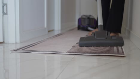 person vacuuming a hallway carpet