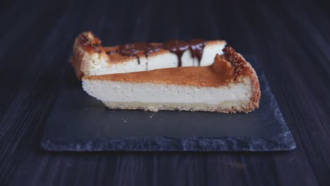 Pouring-chocolate-on-two-slices-of-cheesecake-on-stone-plate-close-up-shoot