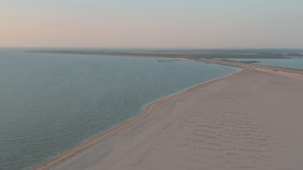 drone cinemático - toma panorámica aérea de la playa de arena natural al atardecer con turistas y personas con buggykiting en zelanda en el mar del norte, países bajos, 30p