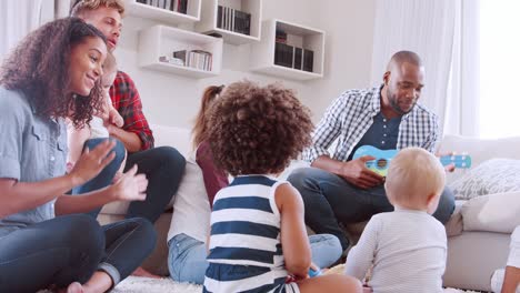amigos con niños pequeños jugando y cantando en el suelo y el sofá