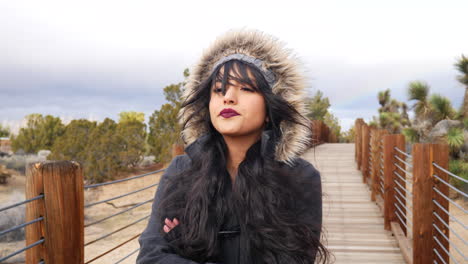 beautiful young woman looking serious on a bridge in the desert in stormy bad weather under cloudy sky slow motion