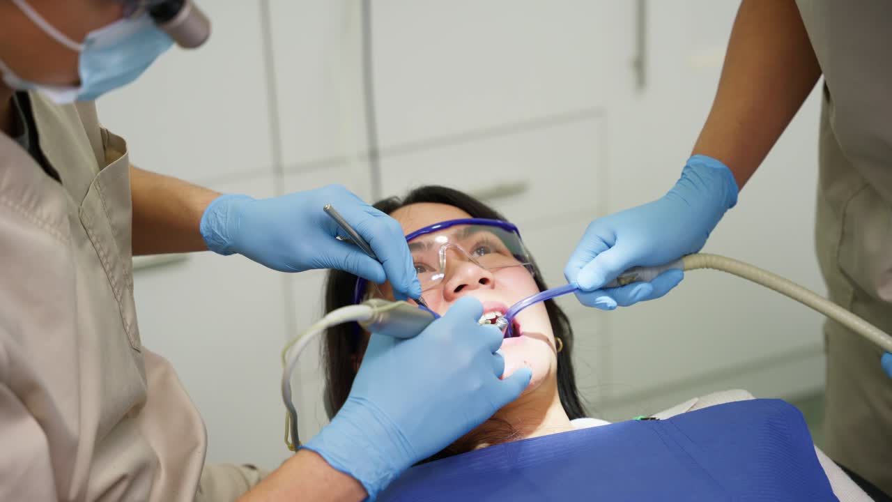 Patient Receiving Dental Treatment from Dentist and Assistant in Clinic