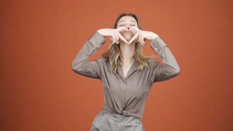 mujer joven haciendo una señal de corazón a la cámara.
