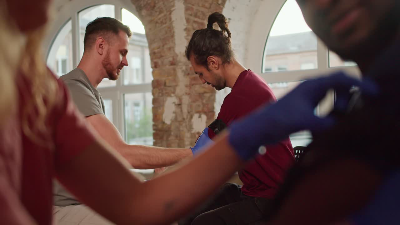 disparo de primer plano: dos pares de personas practican la aplicación de arneses médicos durante un curso de formación práctica para un médico