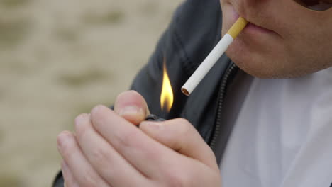 man lights a cigarette wearing leather jacket and aviator sunglasses close up slow motion