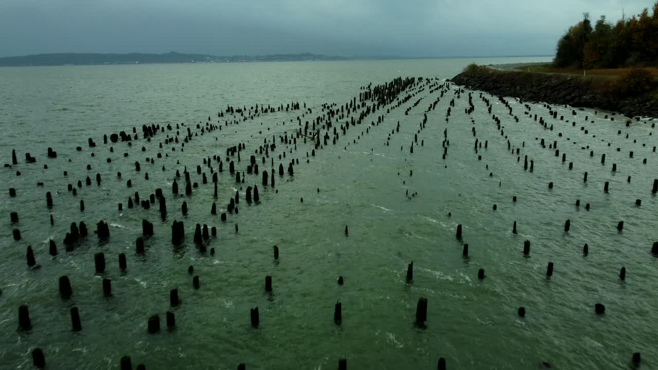 US, WA, Chinook, 2025-10-25 - Drone view of old dock pilings along the Columbia River just before a storm